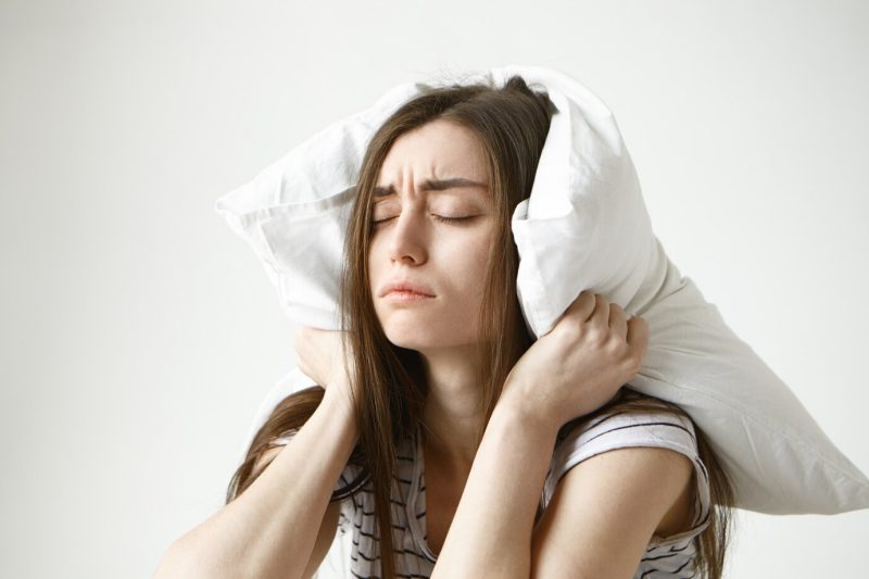 pretty-student-woman-striped-t-shirt-trying-have-some-sleep-sitting-bedroom-with-pillow-her-head-closing-eyes_343059-1447